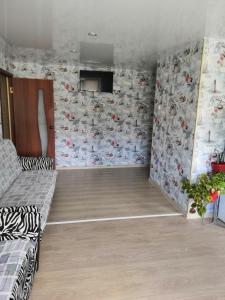 チェベルカにあるUiutnaia kvartira v Teriberkeのソファ付きのリビングルーム、壁紙で覆われたリビングルーム