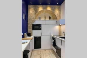 een keuken met witte apparatuur en een bakstenen muur bij CHARMANT STUDIO HYPER CENTRE in Troyes