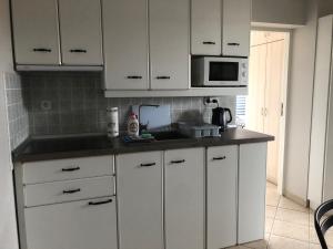 a kitchen with white cabinets and a microwave at Apartament Nordic in Trzęsacz