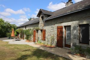 a stone house with a patio and an umbrella at La Longère de La Chevallerais in La Chevallerais