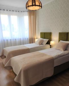 two beds in a room with windows and a chandelier at Panorama Strzyżów in Strzyżów