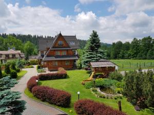 a large wooden house with a garden in front of it at Willa Świdrówka 2 in Poronin