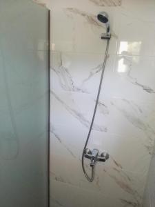 W łazience wyłożonej białym marmurem znajduje się prysznic. w obiekcie Bouganville apartment Stegna w mieście Archangelos