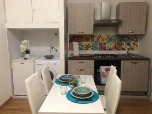 a kitchen with a white table and chairs with plates and bowls on it at MACALELU HOUSE in Vietri sul Mare