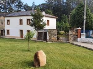 a house with a tree and a rock in the yard at Casa Muiño dos Frades in Lourenzá