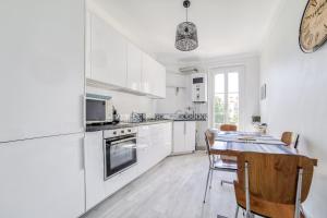 een keuken met witte apparatuur en een tafel met stoelen bij Charming Apt Near The Croisette in Cannes