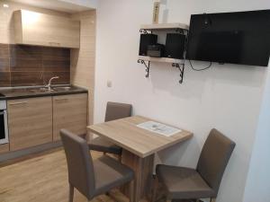 a kitchen with a wooden table with chairs and a sink at APARTMANI MOROVI DVORI in Drage