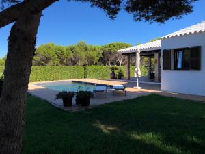 um quintal com uma piscina e uma mesa e uma casa em Villa con piscina Cala Morell em Cala Morell