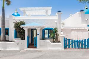 Casa blanca con puertas azules y palmeras en Bahiazul Villas Corralejo by Vreagestion en Corralejo