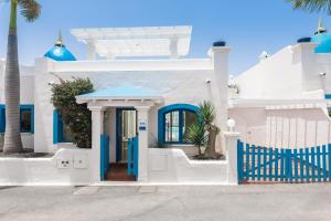 a white house with blue gates and palm trees at Bahiazul Villas Corralejo by Vreagestion in Corralejo