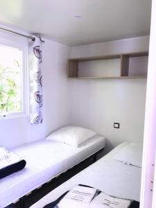 2 Betten in einem kleinen Zimmer mit Fenster in der Unterkunft Le Goh Velin in Saint-Gildas-de-Rhuys