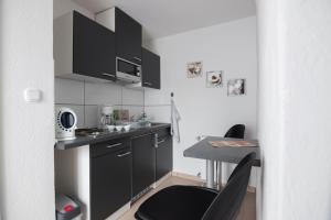 una pequeña cocina con armarios negros y una mesa en Maxbed, en Flensburg