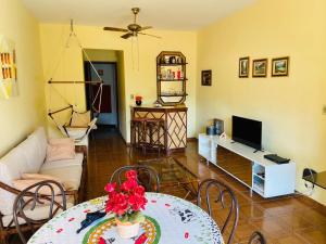 a living room with a table and a television at Apto 2 dorms Enseada in Guarujá