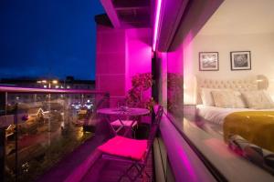 a balcony with a bed and a table with pink lights at Live in Leeds Millenium Square Apartment in Leeds