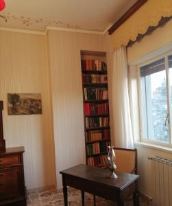 ein Zimmer mit einem Tisch und einem Bücherregal mit Büchern in der Unterkunft Appartamento d'Artista in Piazza Armerina