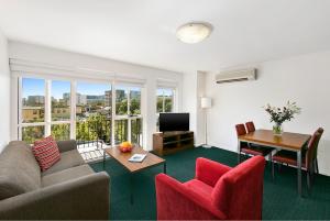 Melbourne Carlton Central Apartment Hotel Official في ملبورن: غرفة معيشة مع أريكة وكراسي ومكتب
