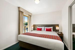 a hotel room with a large bed with red pillows at Melbourne Carlton Central Apartment Hotel Official in Melbourne