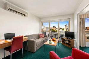 sala de estar con sofá, escritorio y TV en Melbourne Carlton Central Apartment Hotel Official, en Melbourne