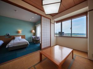 a bedroom with a bed and a table and a window at Ocean Resort PMC in Onna