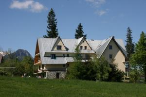 una casa con techo de metal en un campo verde en Willa Pod Kopiencem, en Zakopane