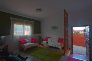 uma sala de estar com um sofá branco e almofadas vermelhas em La Casa del Huerto em Los Baldíos