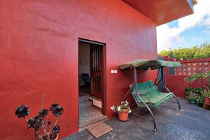 a red house with a green chair on a patio at La Casa del Huerto in Los Baldíos