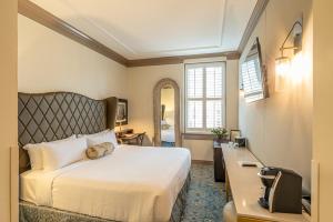 a bedroom with a large white bed and a desk at Andrew Pinckney Inn in Charleston