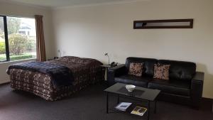a hotel room with a bed and a couch at Tudor Lodge Motel in Hawera