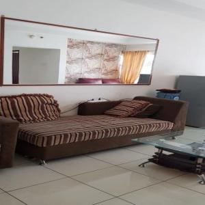 un sofá en la sala de estar con espejo en Mediterania Garden Residence 2, en Yakarta