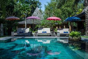 uma piscina de resort com guarda-sóis e cadeiras em The BK Village em Canggu