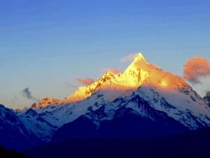 a mountain covered in snow with the sun shining on it at Three Wells Inn in Lijiang