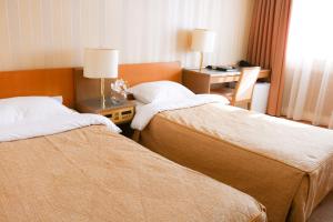 ウラジオストクにあるギャバン ホテルのベッド2台とデスクが備わるホテルルームです。