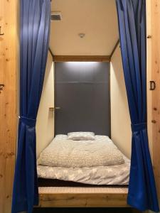 łóżko w pokoju z niebieskimi zasłonami w obiekcie Hostel Furoya w Osace
