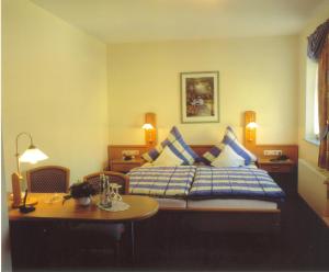 BirresbornにあるHotel zur Kroneのベッド、テーブル、テーブルが備わるホテルルームです。
