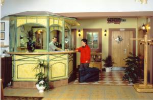a man standing at a counter in a hotel with his luggage at Hotel zur Krone in Birresborn