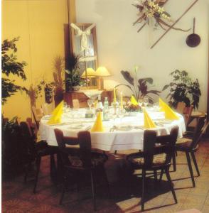 Hotel zur Krone في Birresborn: طاولة غرفة الطعام مع مفرش أبيض و بعرصي صفراء