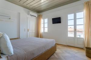a white bedroom with a bed and a window at Guesthouse Niriides in Spetses