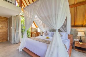 a bedroom with a white bed with a canopy at Lasamana Villas Ubud by Pramana Villas in Ubud