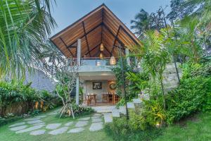 a house with a wooden roof in a garden at Lasamana Villas Ubud by Pramana Villas in Ubud