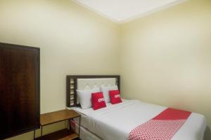 een slaapkamer met een wit bed met rode kussens bij Super OYO 3354 Homia Residence in Mencil