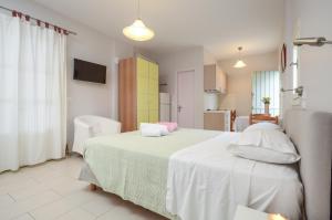1 Schlafzimmer mit einem weißen Bett und einer Küche in der Unterkunft Ydreos Studios & Apartments in Mikri Vigla