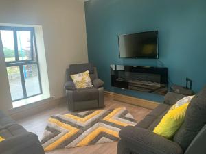 a living room with two chairs and a flat screen tv at The Local Lodge in Longford