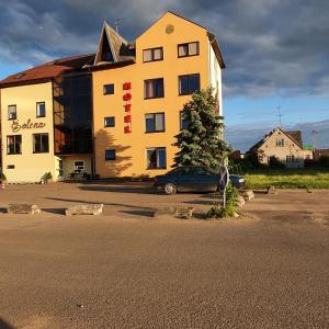 a building with a car parked in a parking lot at Šolena in Alytus
