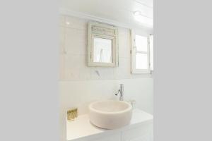 uma casa de banho branca com um lavatório e um espelho em Mooi Mayor em Míconos