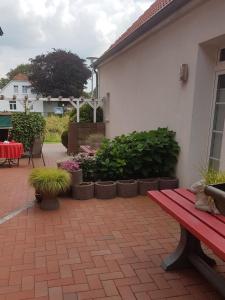 a patio with a red bench and some plants at Ferienwohnungen Blischke in Carolinensiel