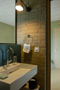 baño con lavabo y pared de ladrillo en BnB Belle5, en Bellerive