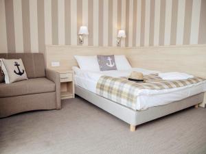 um quarto de hotel com uma cama e uma cadeira em Porto Marina em Krynica Morska