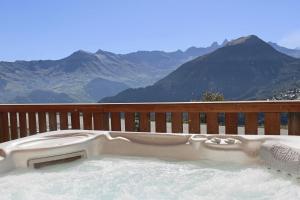 bañera de hidromasaje en una terraza con vistas a las montañas en REFLET DES AIGUILLES - Chalet avec Jacuzzi en La Toussuire