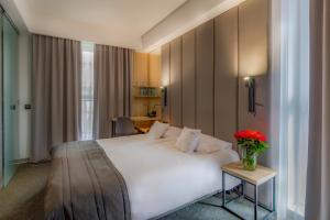 een hotelkamer met een wit bed en een vaas met bloemen bij Bulvar Hotel in Gorzów Wielkopolski