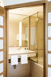 un bagno con un lavandino, una vasca e uno specchio di Novotel Casablanca City Center a Casablanca
